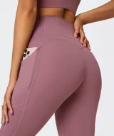 Calza deportiva Fabletics modelo PureLuxe Oasis de tiro alto y largo 7/8, en color malva, con bolsillos laterales de fácil acceso.