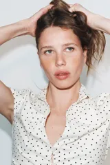 Camisa entallada blanca con estampado de lunares negros, cuello solapa, escote en V y manga corta. Cuenta con frunces frontales y cierre de botones.