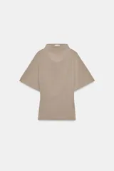 Top fluido color beige, con cuello perkins y mangas por debajo del codo. Bajo redondeado.