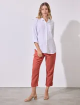Camisa blanca de corte clásico con textura de líneas verticales, cuello con solapa, cierre frontal con botones y bolsillo en el pecho. Presenta mangas tres cuartos regulables con presilla y botón.