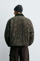 Cazadora de corte cropped confeccionada en algodón con ligero acolchado interior. Presenta un estampado floral en tonos oscuros, cuello de solapa en pana a contraste, cierre frontal con cremallera y bolsillos frontales tipo canguro.