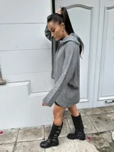 Sweater negro de tejido de punto grueso con cuello alto volcado y corte holgado.