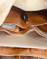 Bolso tote de cuero color marrón claro, con doble asa larga y compartimento interno con separador para computadora y bolsillo para objetos pequeños.