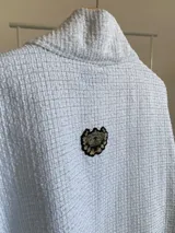 Ruana de diseño estructurado confeccionada en tela tipo tapiz con textura cuadriculada, de corte amplio y caída fluida.