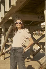 Blusa beige de corte recto con cuello redondo y volados decorativos en los hombros. Presenta mangas cortas abullonadas con terminación elástica.