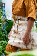 Delantal corto de algodón color crudo con teñido artesanal shibori en tonos marrones.