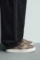 Zapatillas marrones de estilo retro con cordones, capellada de cuero y suela de goma color crema.