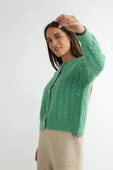 Cardigan de punto gris con diseño de ochos y trenzas, cuello redondo y cierre frontal con botones dorados grandes. Posee mangas largas con puños acanalados.