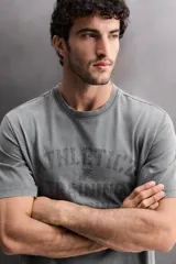 Camiseta de corte regular fit confeccionada en algodón, con cuello redondo y manga corta. Presenta un estampado frontal con el texto 'ATHLETICZ TRAINING CREW' con efecto desgastado.