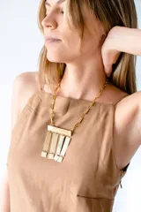 Collar dorado con cadena de eslabones rectangulares y colgante rectangular con flecos de rectángulos pequeños.