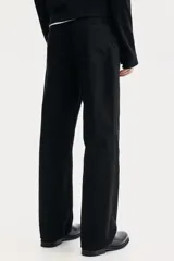 Jean de cinco bolsillos en denim negro, con cintura estándar y cierre de botón. Presenta un corte relajado desde la cadera hasta el bajo, con pierna recta y amplia a partir del muslo.