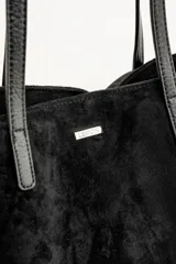 Bolso tipo tote de gran tamaño en color bordó, confeccionado en material con textura similar a la gamuza. Cuenta con doble asa larga para llevar al hombro y una pequeña placa metálica decorativa en el frente.