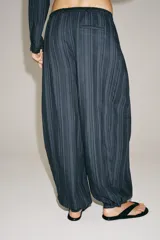 Pantalón bombacho Zara Woman Collection, confeccionado en mezcla de algodón, con tiro medio, cintura elástica y cordón ajustable. Presenta diseño a rayas sutiles, bajo abullonado con puño y cierre frontal con botón.