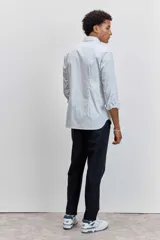 Camisa de manga larga con cuello clásico y cierre frontal de botones. Presenta un diseño de rayas verticales finas en tonos claros.