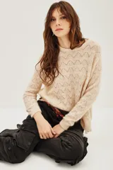 Sweater de punto con diseño calado geométrico, cuello redondo y mangas largas. Confeccionado en una mezcla de lana y alpaca, presenta una textura suave y ligera.
