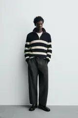 Bota de caña media fabricada en piel color negro, con detalle de arnés y hebilla metálica lateral. Presenta horma cuadrada y suela a tono con ligero tacón.