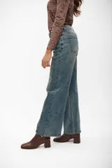 Pantalón de jean corte wide leg, color azul medio, con costuras verticales decorativas en el frente y tiro alto.