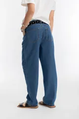 Pantalón de denim azul índigo, de tiro medio-alto, con tablas en la cintura, corte recto y bolsillos laterales y traseros.