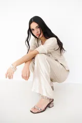 Pantalón de lino color beige con brillo, de corte palazzo y tiro alto.