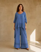 Pantalón azul de corte ancho y relajado, confeccionado en lino, con detalle de tejidoado geométrico en el ruedo.
