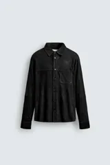 Sobrecamisa de corte regular confeccionada en piel con acabado de ante. Presenta cuello solapa, cierre frontal con botones, manga larga con puños abotonados y un bolsillo de parche en el pecho.