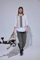 Chaleco de tejido de punto con diseño de bloques de color en tonos tierra, incluyendo marrón, verde oliva y beige. Presenta un panel central con textura tejida y cuello redondo.