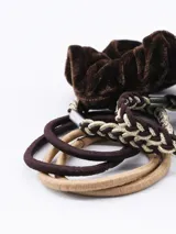 Set de nueve coleros para el pelo en tonos marrones, beige y dorado. Incluye coleros de terciopelo, trenzados y lisos.