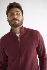 Campera tejida de algodón color bordó, con cierre frontal completo, cuello alto y logo bordado en el pecho.