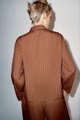 Camisa de viscosa de la colección ZW de Zara, con diseño de rayas verticales, cuello mao y cierre frontal con alamares. Tiene mangas largas y bolsillos frontales de parche.