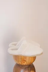 Pantuflas de corderito color blanco, ideales para usar en casa.