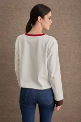 Remera de manga larga color marrón, con cuello en tono verde claro y puños en tono celeste. Presenta el logo de la marca bordado en el pecho.
