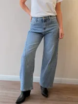 Jeans de denim azul claro con corte balloon fit, silueta amplia en las piernas y costuras curvas decorativas en el frente.