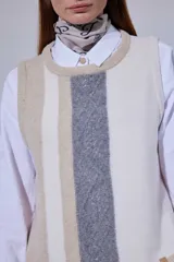 Chaleco de tejido de punto con diseño de bloques de color en tonos tierra, incluyendo marrón, verde oliva y beige. Presenta un panel central con textura tejida y cuello redondo.