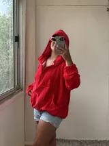 Buzo rojo de plush con capucha, bolsillo, cuello con cierre y elástico ajustable en el ruedo.