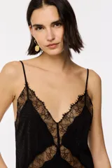 Vestido largo negro de jacquard, con tirantes finos ajustables, escote en V y falda evasé con aberturas laterales. Cuenta con apliques de encaje transparente en el busto, el centro y el bajo.