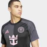 Camiseta de fútbol Adidas alternativa del Inter Miami CF, color negro y gris oscuro con diseño dividido verticalmente. Presenta detalles en rosa, incluyendo el logo de Adidas, el escudo del club y un gráfico central que simula un ancla con corona.