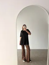 Pantalón tipo oxford de tiro alto con estampado animal print de leopardo, corte ajustado en la parte superior y acampanado desde la rodilla hacia abajo.