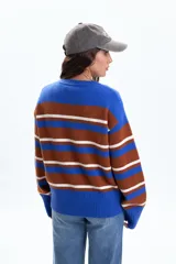 Buzo de punto con diseño de rayas horizontales en tonos azul, marrón y blanco. Presenta cuello redondo, mangas largas y puños anchos acanalados.