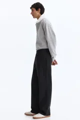 Pantalón sastrero color negro de corte relajado, confeccionado en mezcla de algodón y lyocell, con pliegues frontales y bolsillos laterales.
