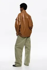 Cazadora de corte oversize confeccionada en piel, con cremallera metálica frontal oculta, cuello subido y manga larga con forma. Cuenta con bolsillos tipo alforja.
