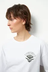 Remerón unisex blanco de manga corta y cuello redondo, con estampado pequeño de una flor en el frente.