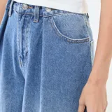 Jean de corte wide leg y tiro alto, confeccionado en denim azul. Presenta pinzas en la cintura, cierre frontal con botón y bolsillos laterales.