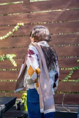 Bufanda tejida de algodón con diseño de rombos en tonos beige, bordó, rosa y mostaza. Presenta una etiqueta de cuero sintético con logo en uno de sus extremos.