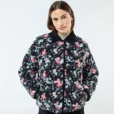 Chaqueta corta con estampado floral en tonos rosa y celeste sobre fondo negro. Tiene cuello mao y cierre frontal con botones a presión.