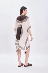 Vestido corto sin mangas color crudo, con escote en V y ajuste en el busto mediante lazos. Presenta un estampado geométrico en tonos marrones y negros.