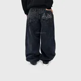 Jean ultra baggy de corte amplio y tiro medio, color negro con efecto acid wash y bordado de llamas en el bolsillo trasero.