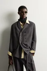 Blazer cruzado de corte relaxed fit, confeccionado en mezcla de lana de color marrón oscuro jaspeado. Presenta solapas de muesca, doble botonadura frontal multiposición y bolsillos con solapa en la cadera.