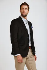 Blazer de pana color marrón oscuro, con cierre frontal de dos botones, solapas clásicas y bolsillos laterales con solapa. Presenta un diseño estructurado y elegante.