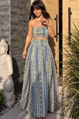 Conjunto compuesto por un top strapless escote tipo banda y una falda larga de corte amplio, ambos con diseño estampado de inspiración étnica en tonos azules, amarillos y verdes.