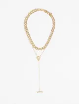 Collar doble dorado compuesto por un choker de cadena gruesa y un collar largo de cadena fina con un nudo decorativo y un dije de barra.